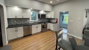 Une cuisine moderne avec des meubles blancs, un plan de travail noir et un plancher en bois.