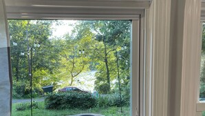 Une fenêtre donnant sur un jardin, avec notamment une structure circulaire en pierre et une végétation luxuriante tout autour.