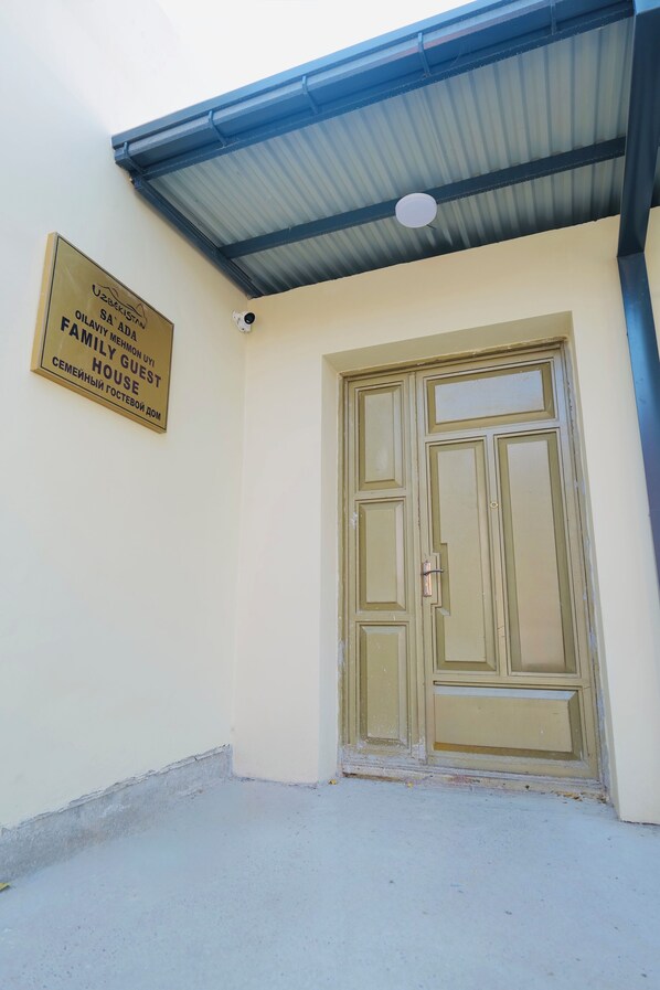 A building entrance with a sign reading "UZBEKISTAN SA ARD MIMON U1 FAMILY GUEST HOUSE".