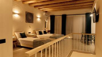 Une chambre d’hôtel avec deux lits, un plafond en bois, un balcon avec une balustrade et un coin repas avec des chaises.