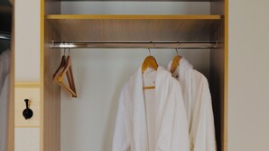 A walk-in closet with wooden shelves and a hanging rod for robes. - saada boutique studios (Bukhara)