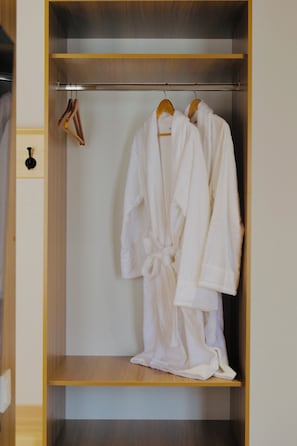 A walk-in closet with wooden shelves and a hanging rod for robes. - saada boutique studios (Bukhara)