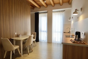 A modern kitchen with a wooden ceiling, a dining area with a table and chairs, and a counter with a coffee maker. - saada boutique studios (Bukhara)