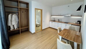 A modern kitchen with wooden cabinets, a dining table, and a built-in oven. - saada boutique studios (Bukhara)