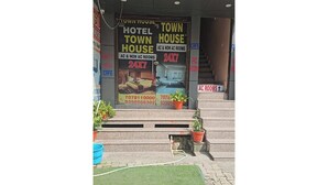 A hotel entrance with a sign advertising AC and non-AC rooms, a 24x7 availability, and contact numbers. - Town house cafe and hotel (Kurukshetra)