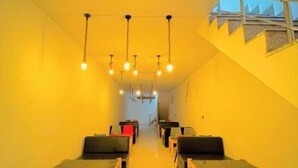 A hotel corridor with rows of seating, a staircase on the right, and hanging lights. - Town house cafe and hotel (Kurukshetra)