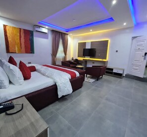Una habitación de hotel moderna con una cama grande, un escritorio, un televisor y un armario.