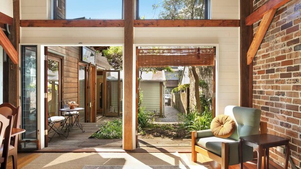Un interior espacioso con un área de patio, pisos de madera y vista al jardín trasero.