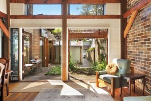 Un interior espacioso con un área de patio, pisos de madera y vista al jardín trasero.
