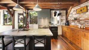 Una cocina con una isla grande, armarios de madera y ollas colgantes.