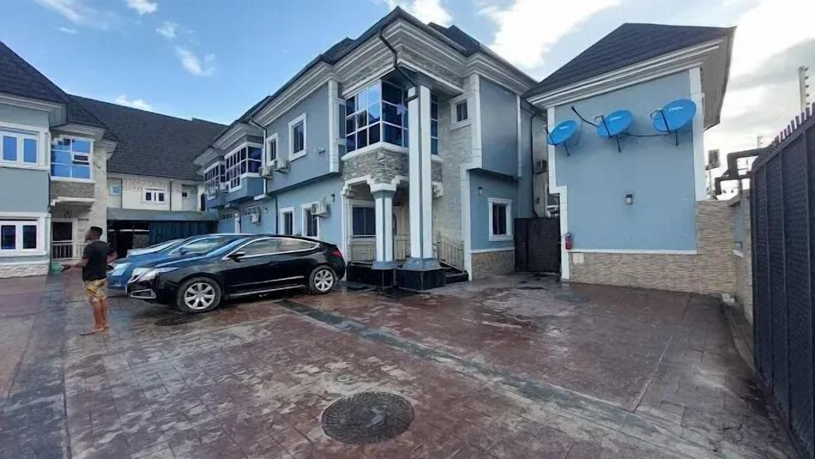 Ein zweistöckiges Haus mit Garage, Satellitenschüsseln und befestigter Auffahrt.
