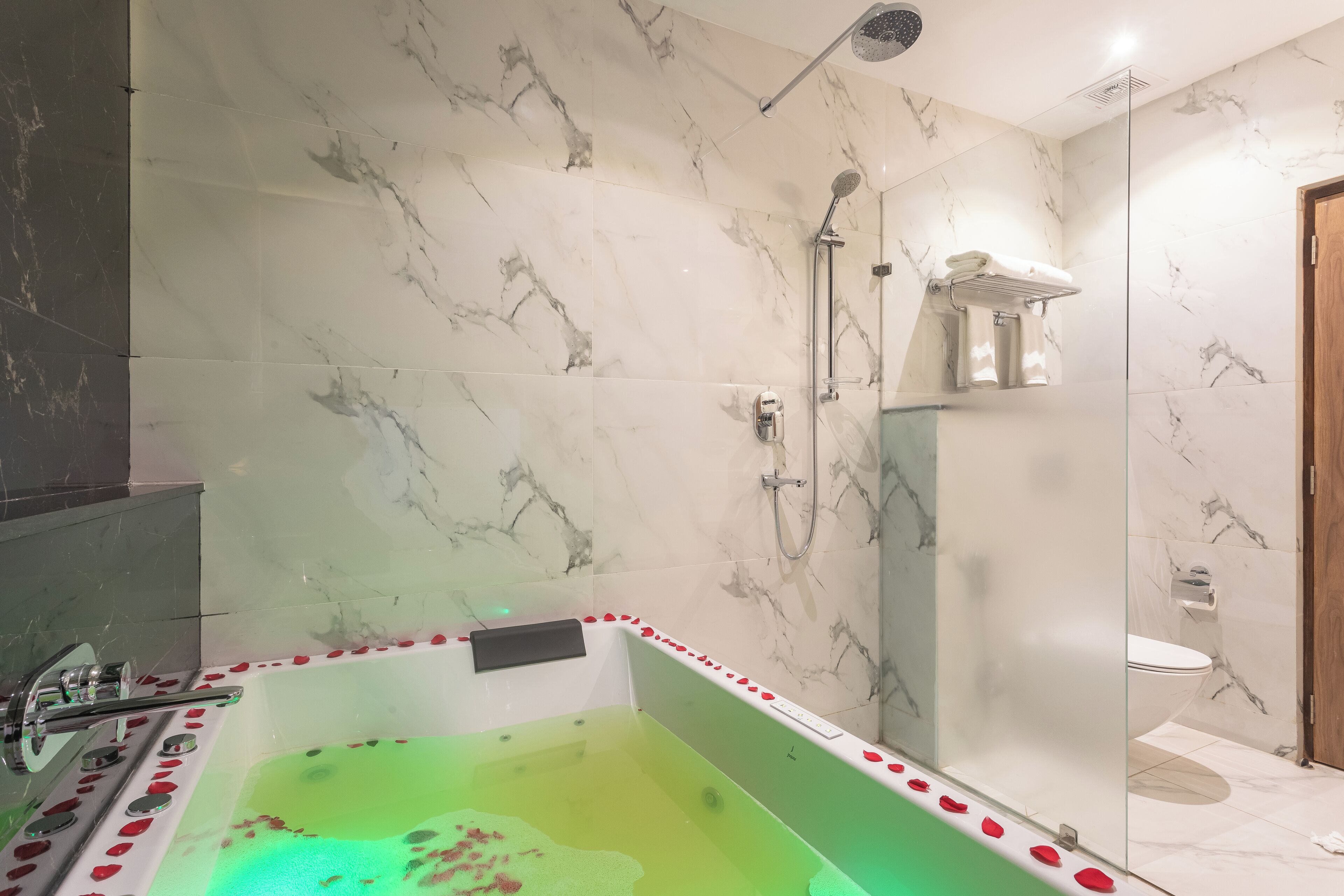 A modern bathroom with a freestanding bathtub, a glass-enclosed shower, and marble walls.
