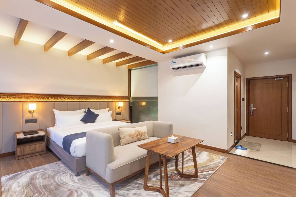 Una habitación de hotel moderna con una cama, un sofá, una mesita de madera y una mesita de noche.