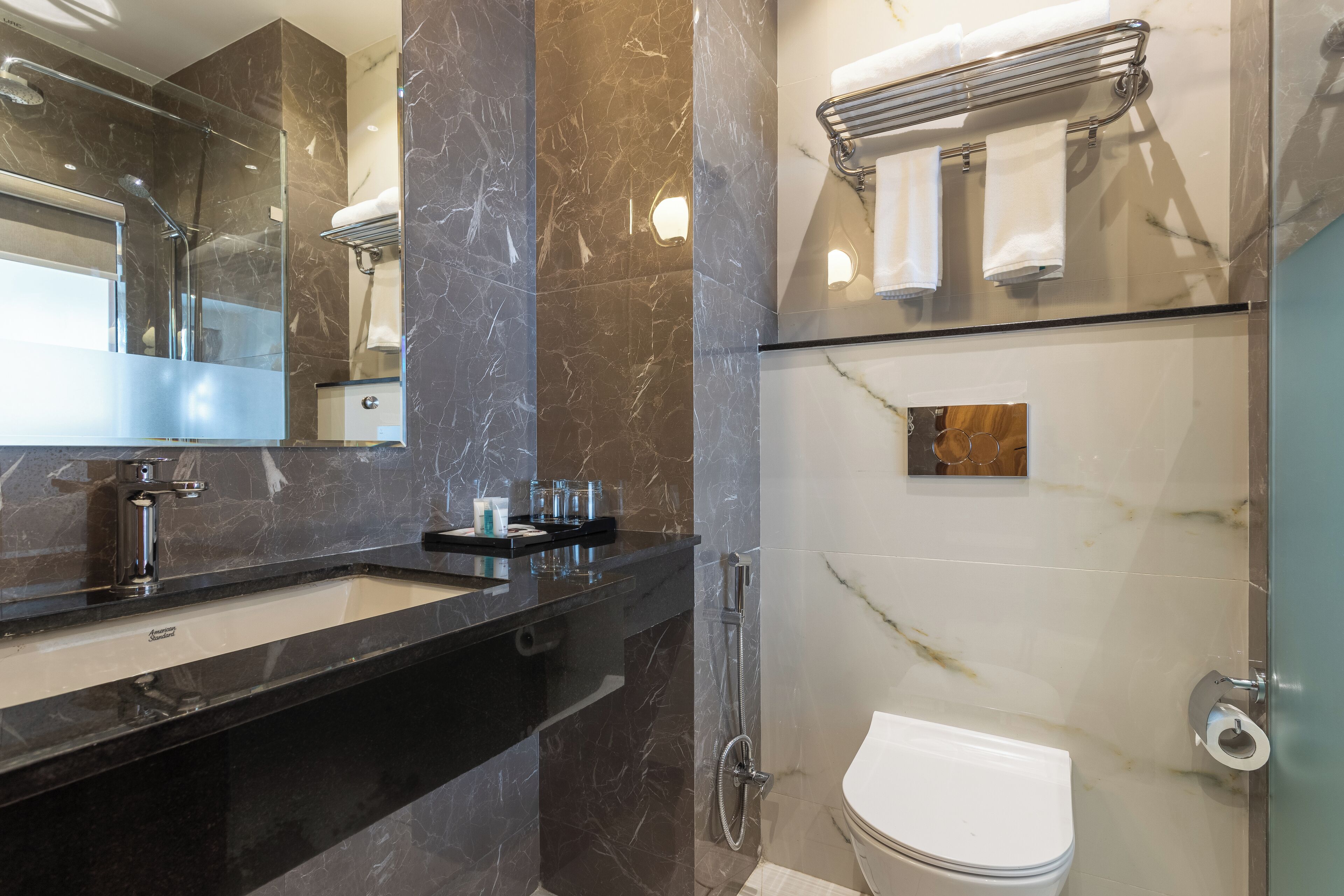 A modern bathroom with a black countertop, a glass shower enclosure, and a toilet.