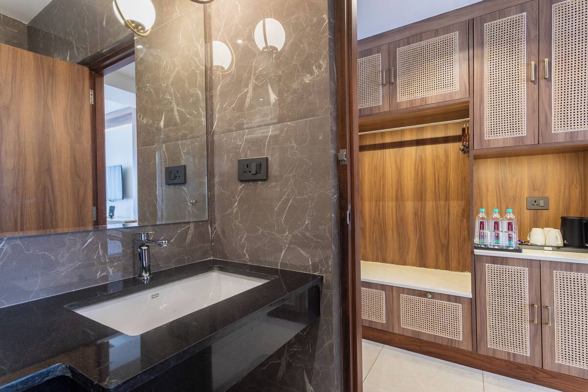Un baño moderno con lavamanos de mármol, armarios de madera y un espejo.