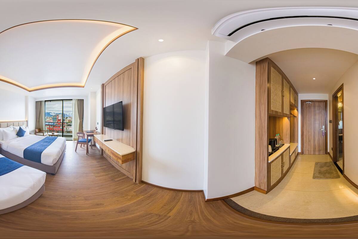 Una habitación de hotel moderna con techo curvo, dos camas, un escritorio y un televisor.
