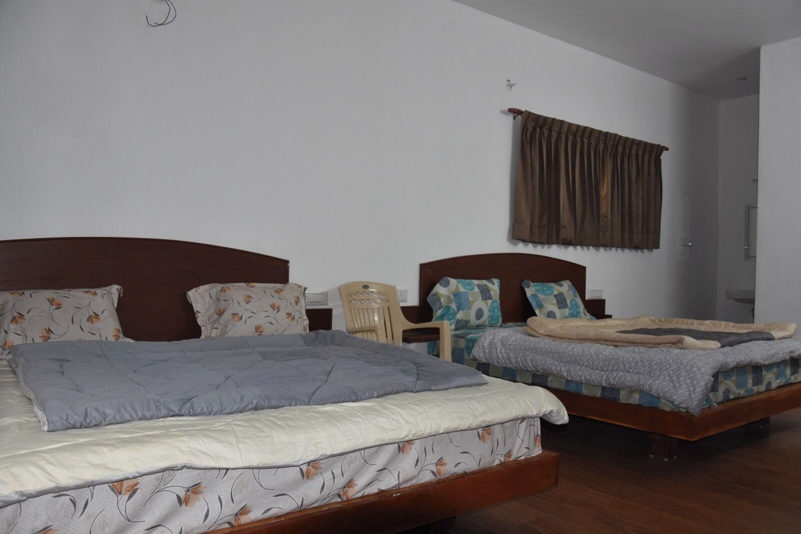 Un dormitorio con dos camas, cada una con ropa de cama estampada con motivos florales y cabeceros de madera.