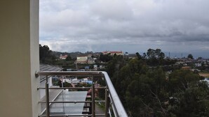 Un balcón con barandilla de metal que da a una vista de un pueblo con edificios y árboles.