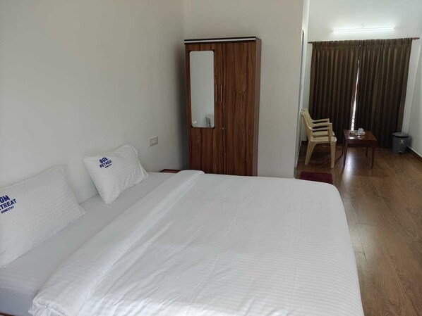 Una habitación de hotel con una cama grande, un armario de madera, un escritorio y una silla.