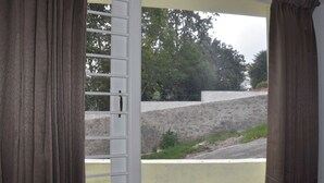 Una habitación con ventana que da a un muro de piedra y vegetación.