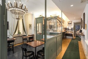 A restaurant with a green counter, wooden tables, and black chairs. There is a chandelier hanging from the ceiling. - Relais Donna Lucrezia Suites (Rome)