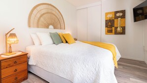A bedroom with a bed, bedside table, lamp, and artwork on the wall. - Modern Guesthouse with Private Pool • Close to Beaches, Shops & Restaurants • (Punaauia)