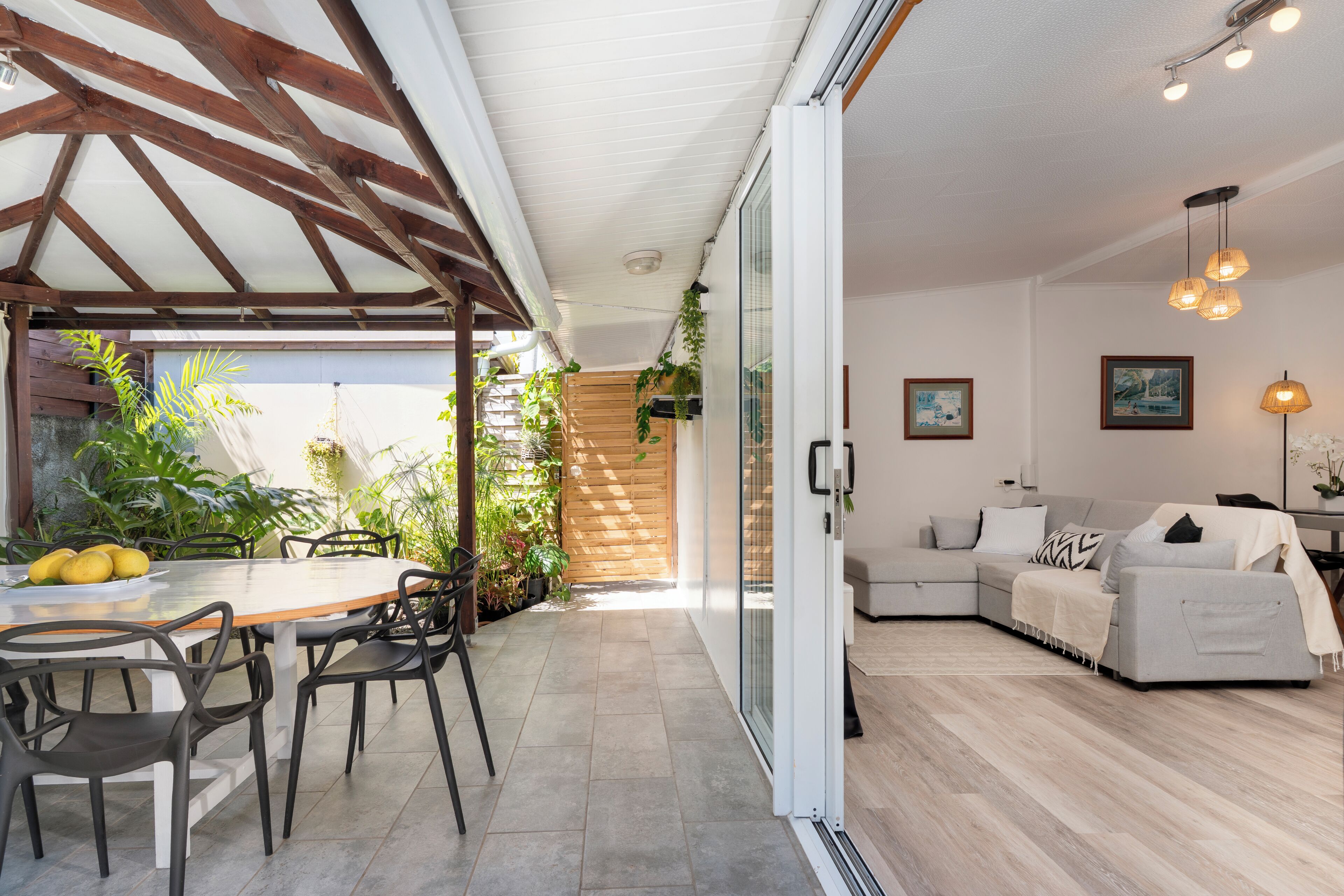 Een moderne woonkamer met een bank, een eettafel met stoelen, en een keuken met een houten plafond.
