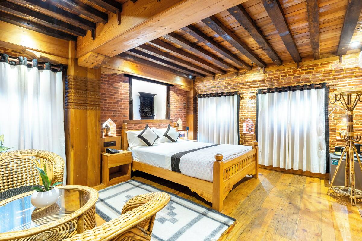 A wooden-framed room with a bed, a wicker table, and a small window.