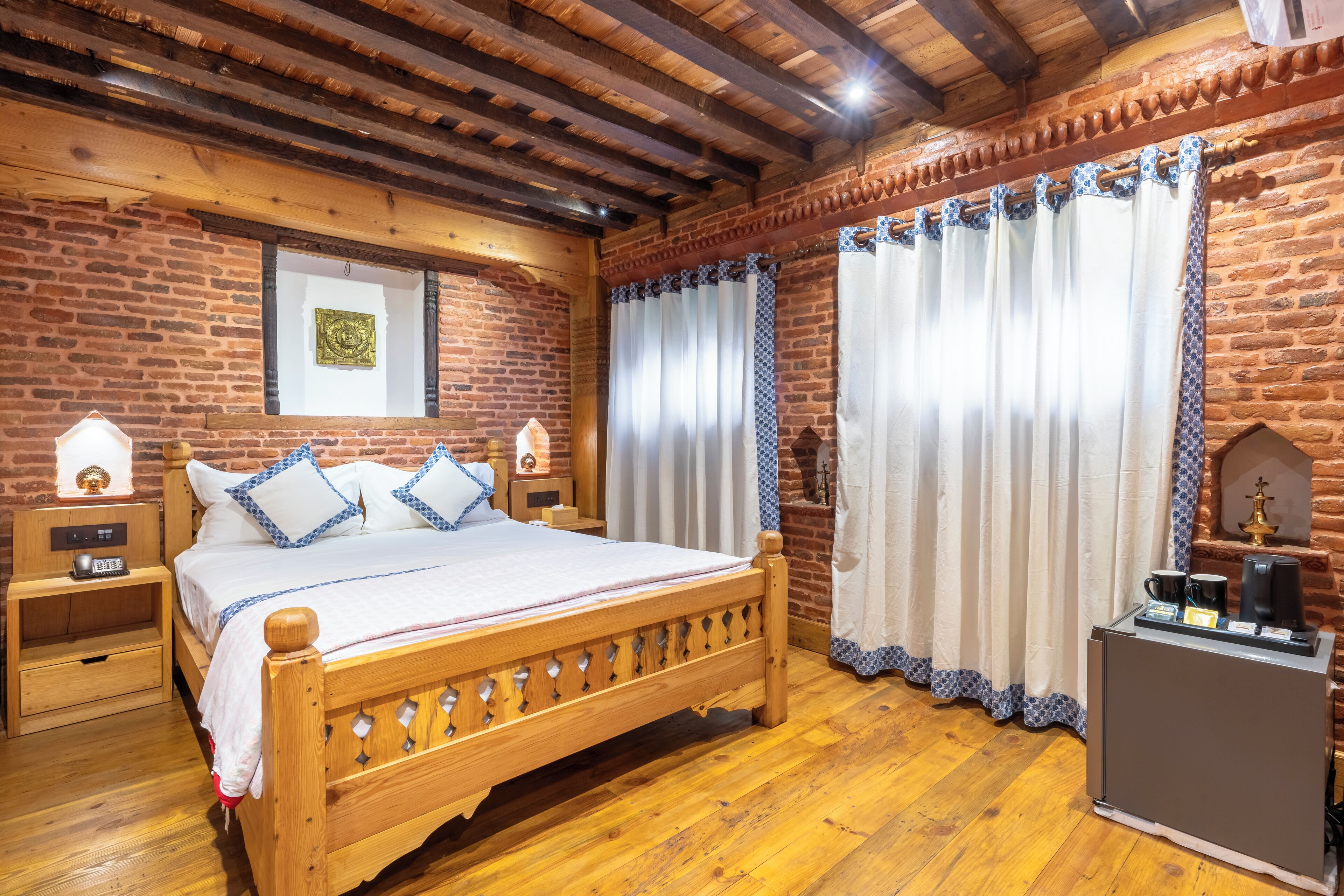 A wooden bed with a headboard, two bedside tables, a nightstand, and a coffee maker on a dresser.