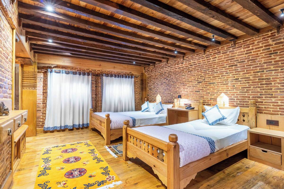 A room with two wooden beds, a brick wall, and a wooden ceiling.