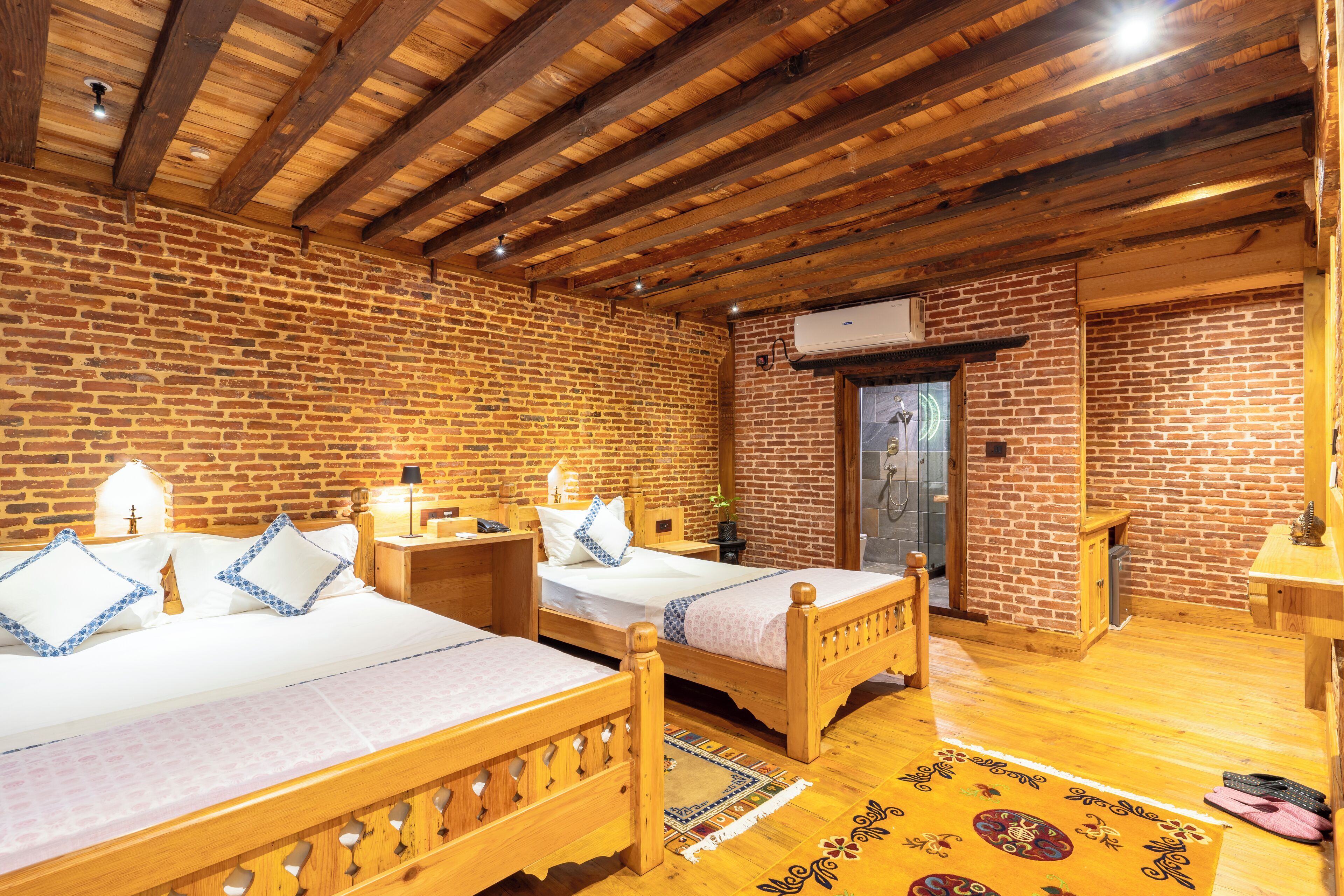 A room with two wooden beds, a brick wall, and a wooden floor.