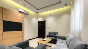 A modern living room with grey sofas, a wooden coffee table, and a black entertainment unit. -  Arjan Park alkhalij (Riyadh)
