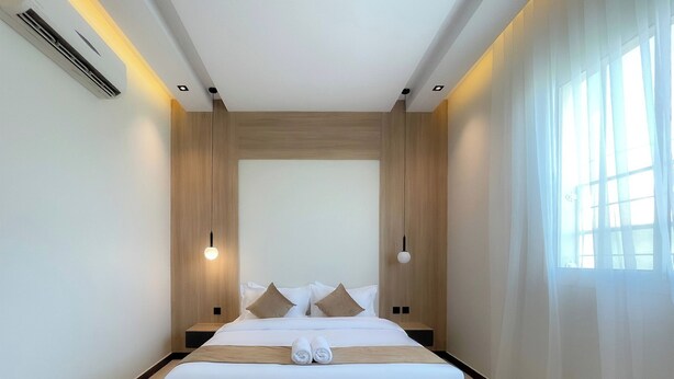 A modern hotel room with a large bed, wooden paneling, and a large window with sheer curtains. -  Arjan Park alkhalij (Riyadh)