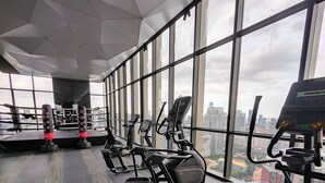Een sportschool met trainingsapparatuur, grote ramen en uitzicht over de stad.