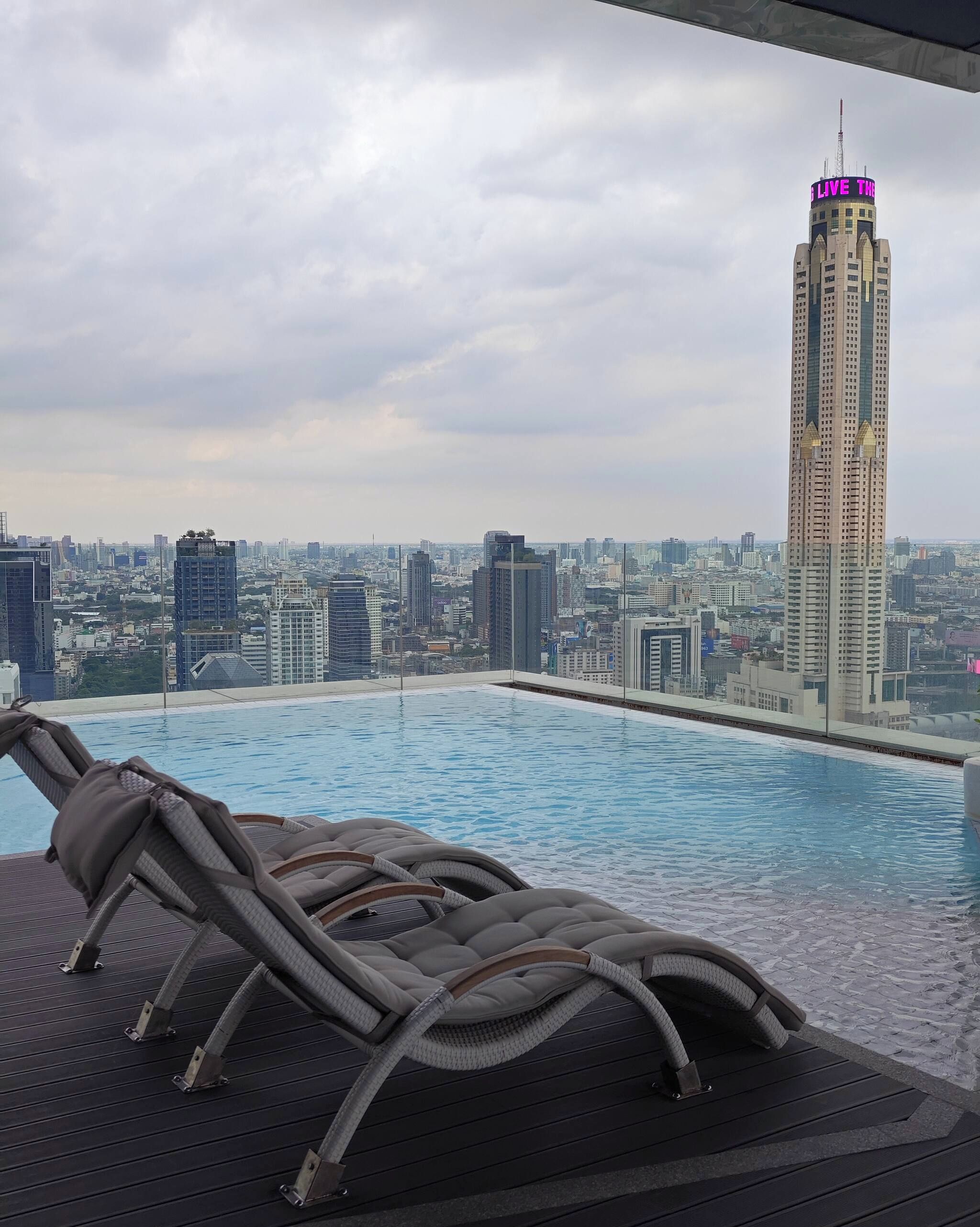 A rooftop pool with lounge chairs and a cityscape view.