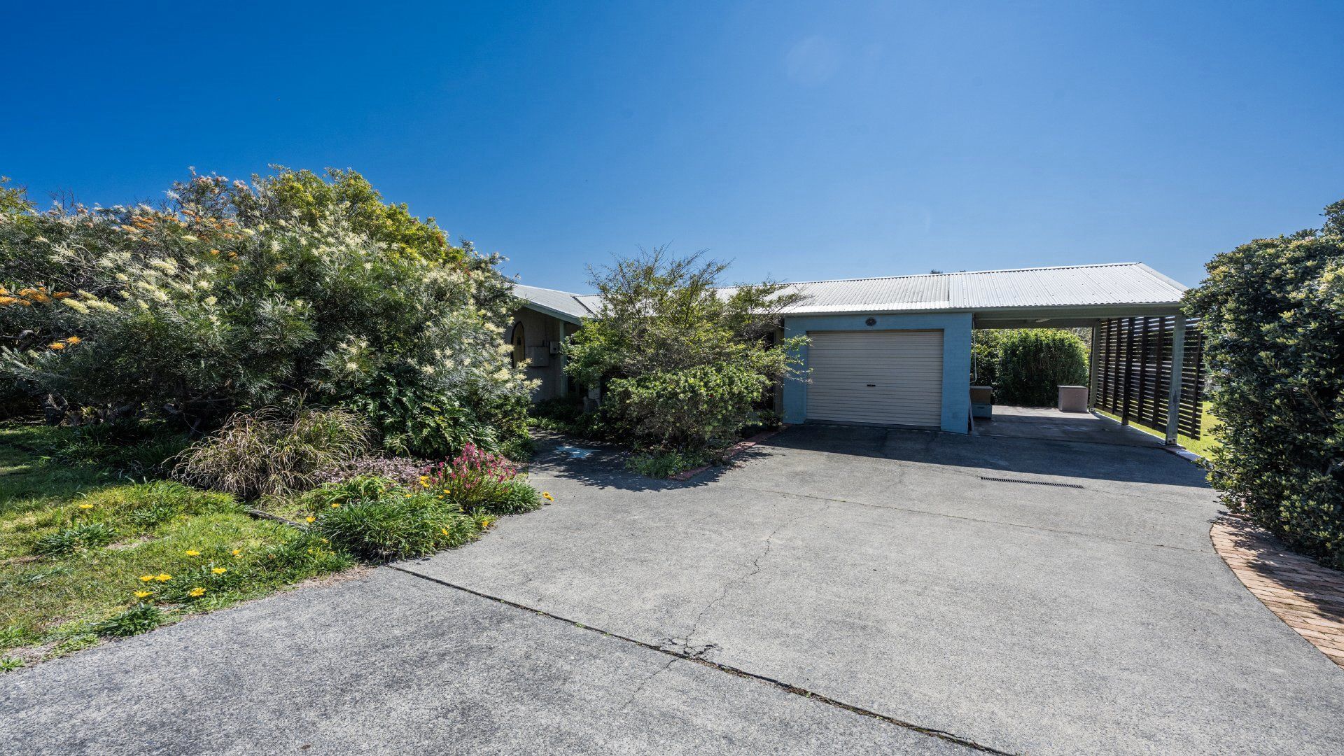 A residential property with a garage, covered driveway, and landscaped garden.