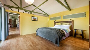 A bedroom with a wooden bed, a small bedside table, and a view of a hallway. - Magic Beach - Lifestyle Minnie Water (MINNIE WATER)