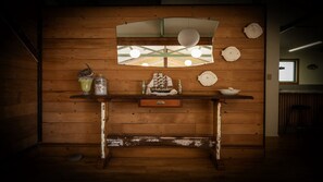 Un mur en bois avec une fenêtre, une étagère ornée d’objets décoratifs et une petite table.