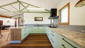 A modern kitchen with a central island, a built-in stove, and a large window. - Magic Beach - Lifestyle Minnie Water (MINNIE WATER)