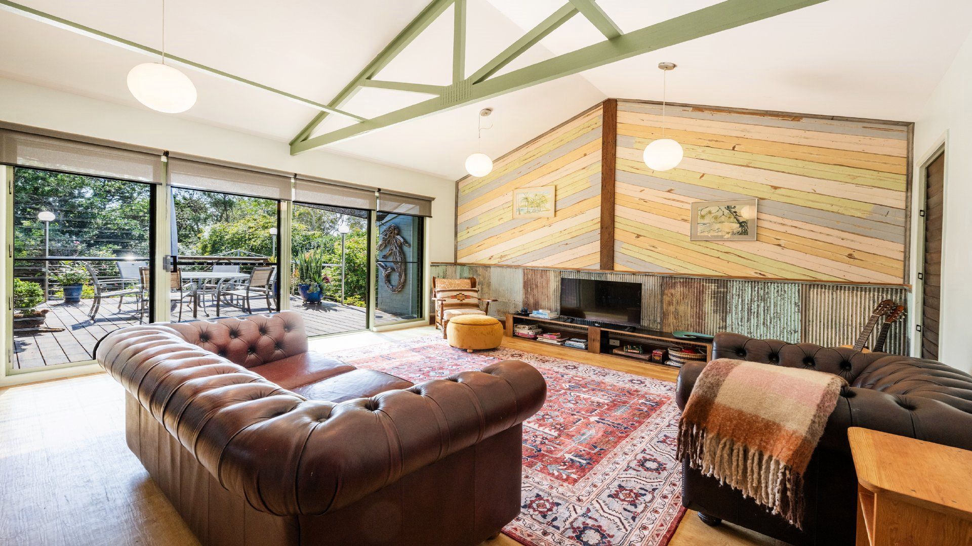 A modern living room with a large sectional sofa, a flat-screen TV, and a wooden accent wall.