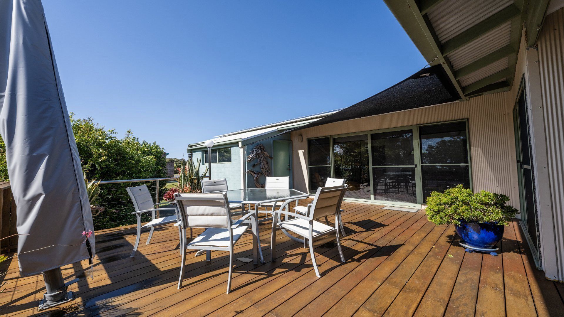 En træterrasse med en glasdør, der fører til en overdækket patio.