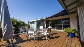 Une terrasse en bois avec une porte vitrée donnant sur un patio abrité.