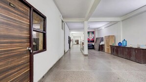 A hallway with a wooden door labeled "102", a water dispenser, and a framed picture on the wall. - Hotel Heaven Peacock Noida (Noida)