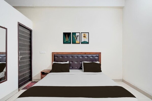 A bedroom with a bed, a headboard, a nightstand, and three wall art pieces.