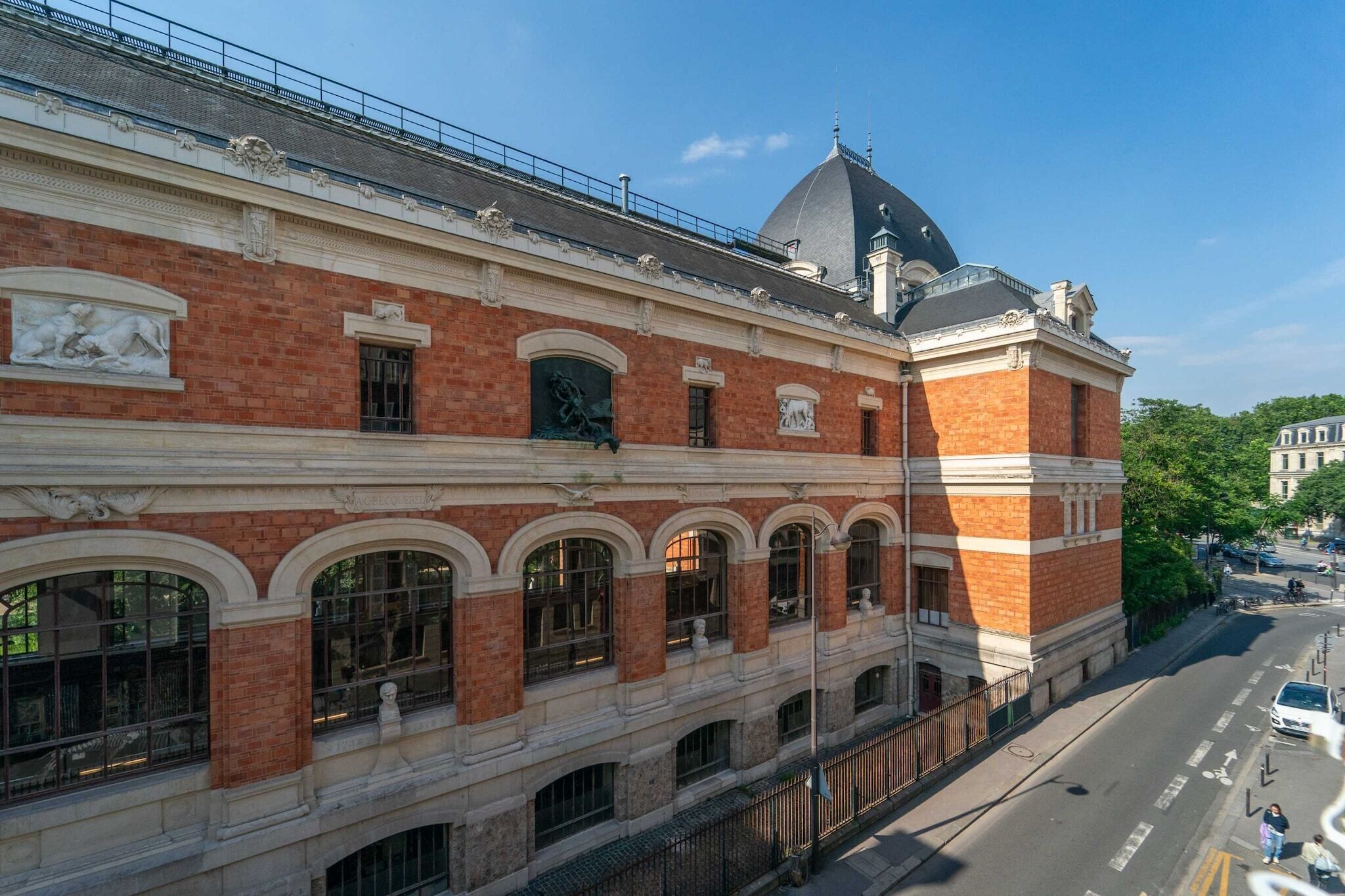 A historic building with red brick facade, arched windows, and a dome on the roof.