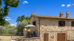 A stone house with a patio, outdoor seating, and a fenced garden.