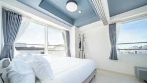 Una camera d'albergo moderna con un ampio letto, vista sulla città e un balcone.