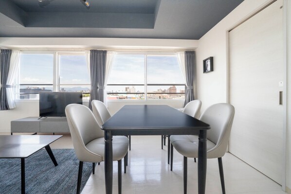 A modern dining area with a table and chairs, a sofa, and a TV.