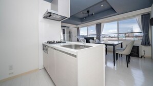 Una cucina moderna con isola centrale, zona pranzo con tavolo e sedie, e ampie finestre con vista sulla città.