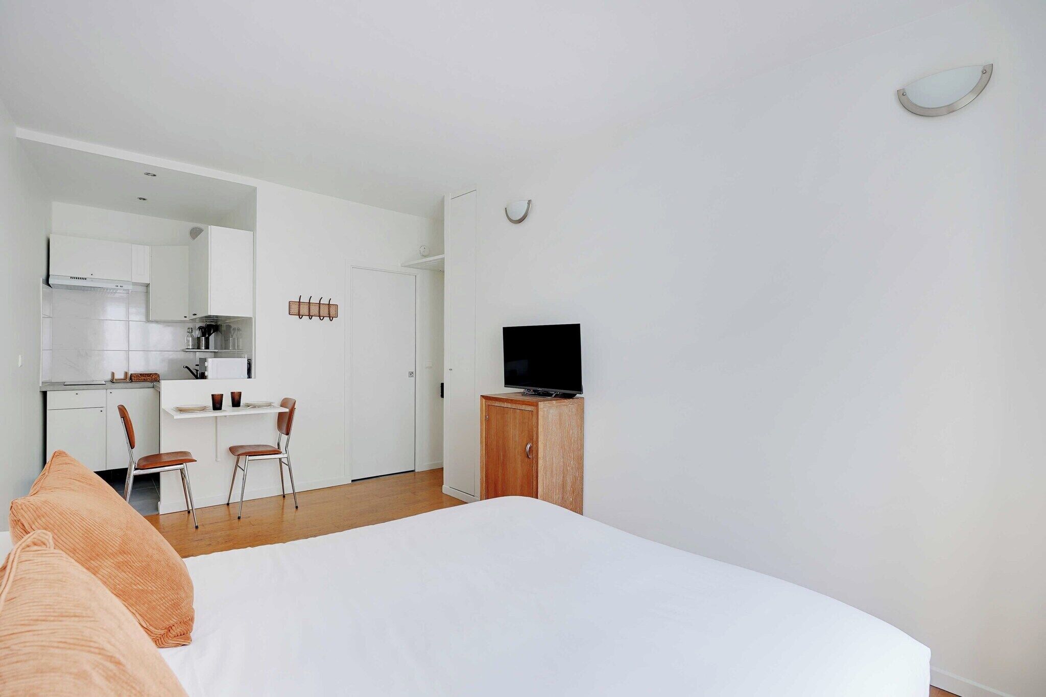 Une chambre moderne équipée d’un lit, d’une télévision, d’une armoire en bois et d’un coin cuisine.